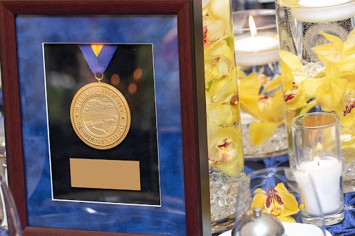 photo of framed president's medal in front of yellow flowers and white candles