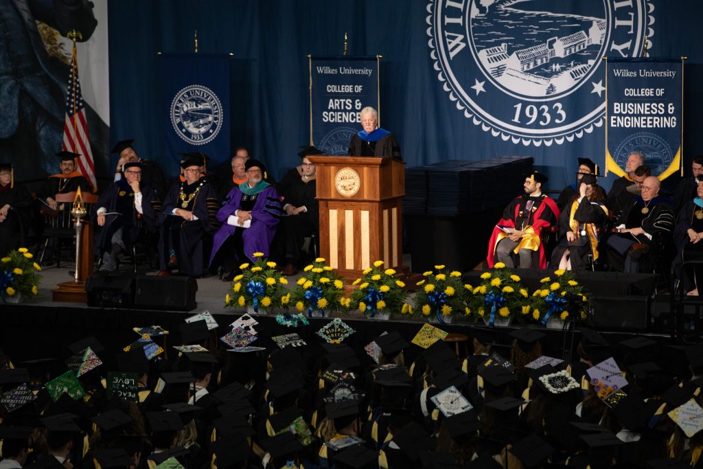 a photo of the platform party on stage and graduates in the audience