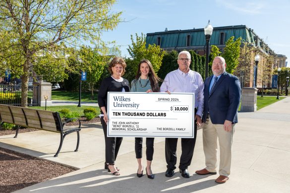 Four people standing on Wilkes campus with an oversized check