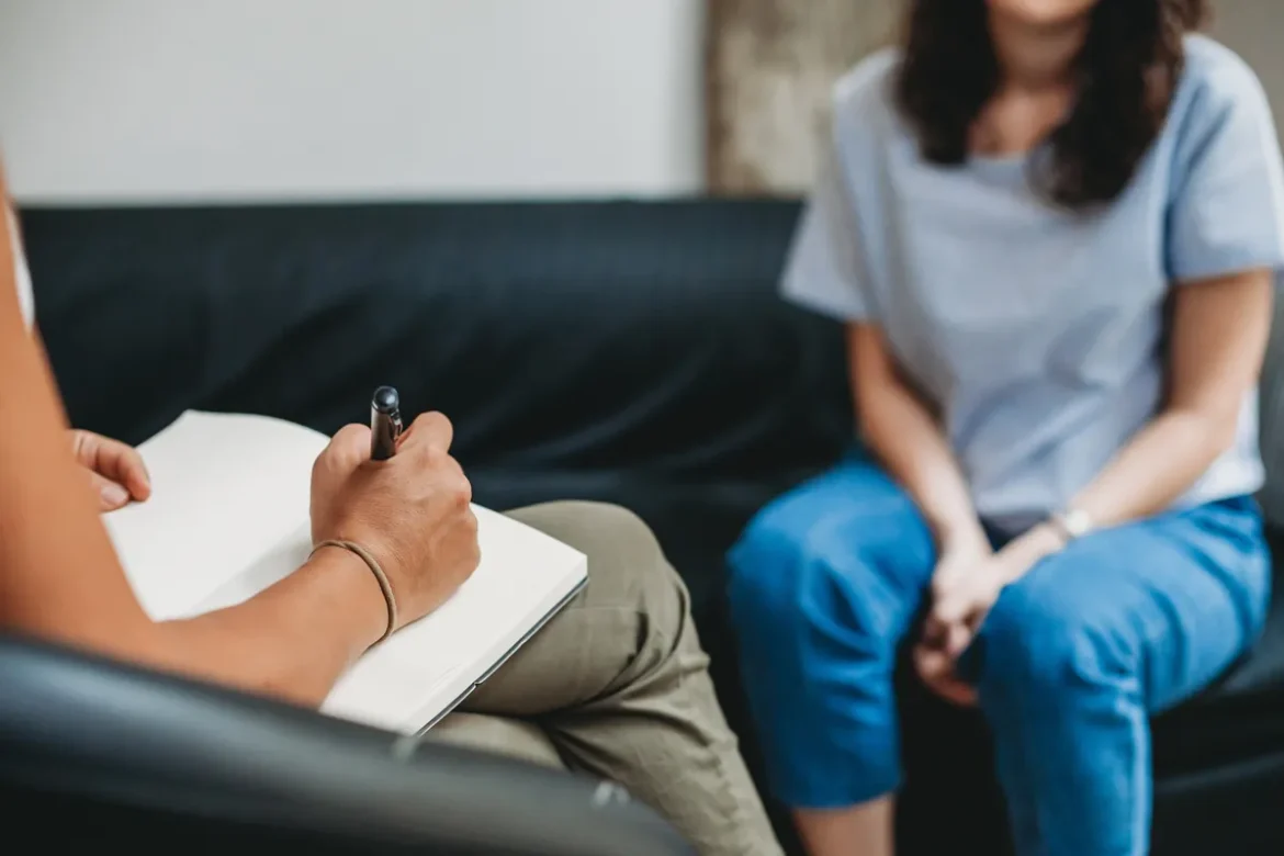 stock photo of therapist taking notes during a student meeting -- no faces are shown