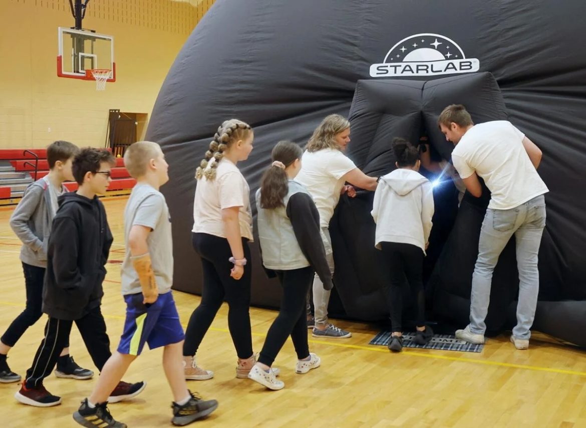 A line of students walk in to an inflatable planetarium