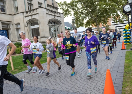 Race participants running past Weckesser Hall on the Wilkes campus