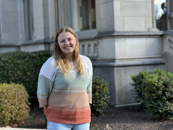 Photo of young woman with long hair smiling in front of Weckesser Hall