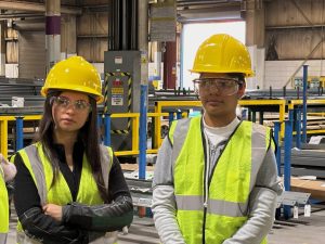 Students in a factory in hardhats, goggles and safety vests