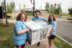 Students carry a refrigerator box