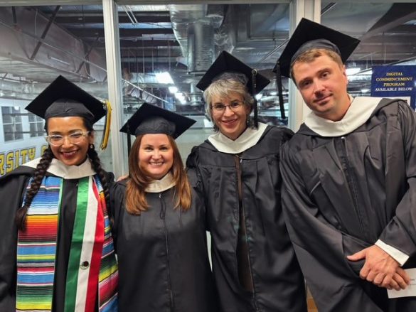 Four graduates in caps and gowns gather before the ceremony